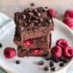 berries with stacked up brownies on a white plate